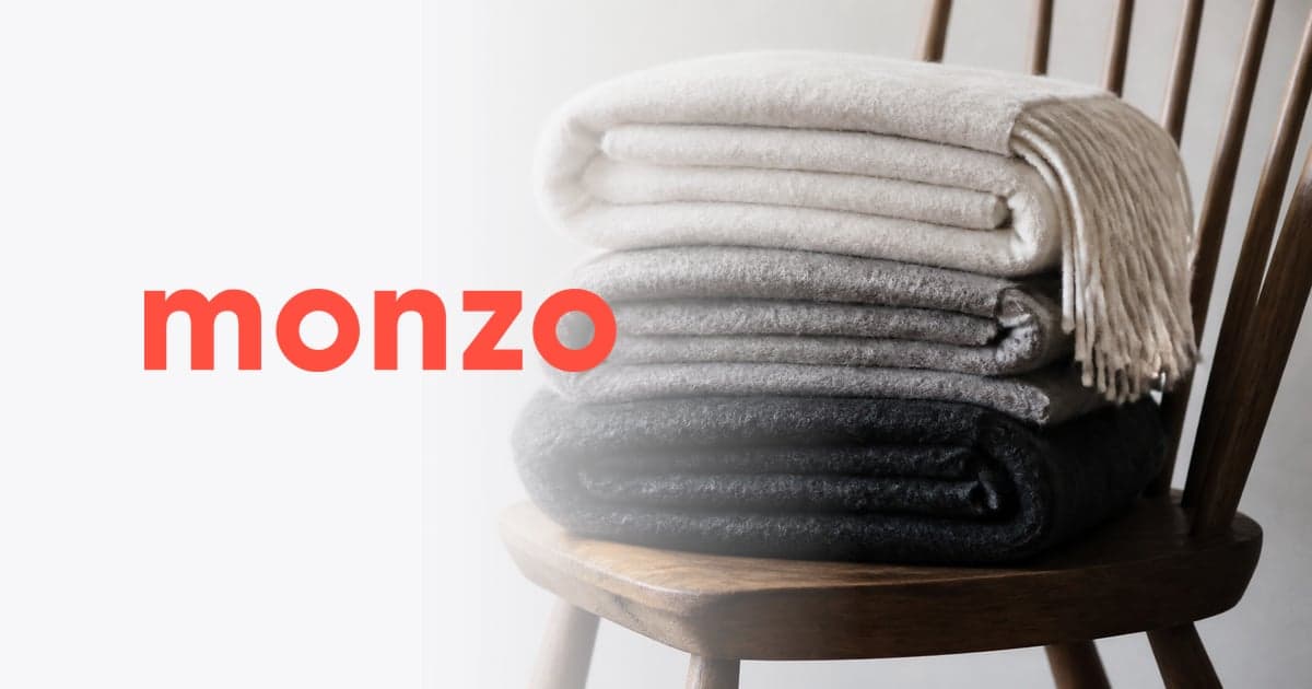 three folded wool blankets of different weights stacked on a wooden chair