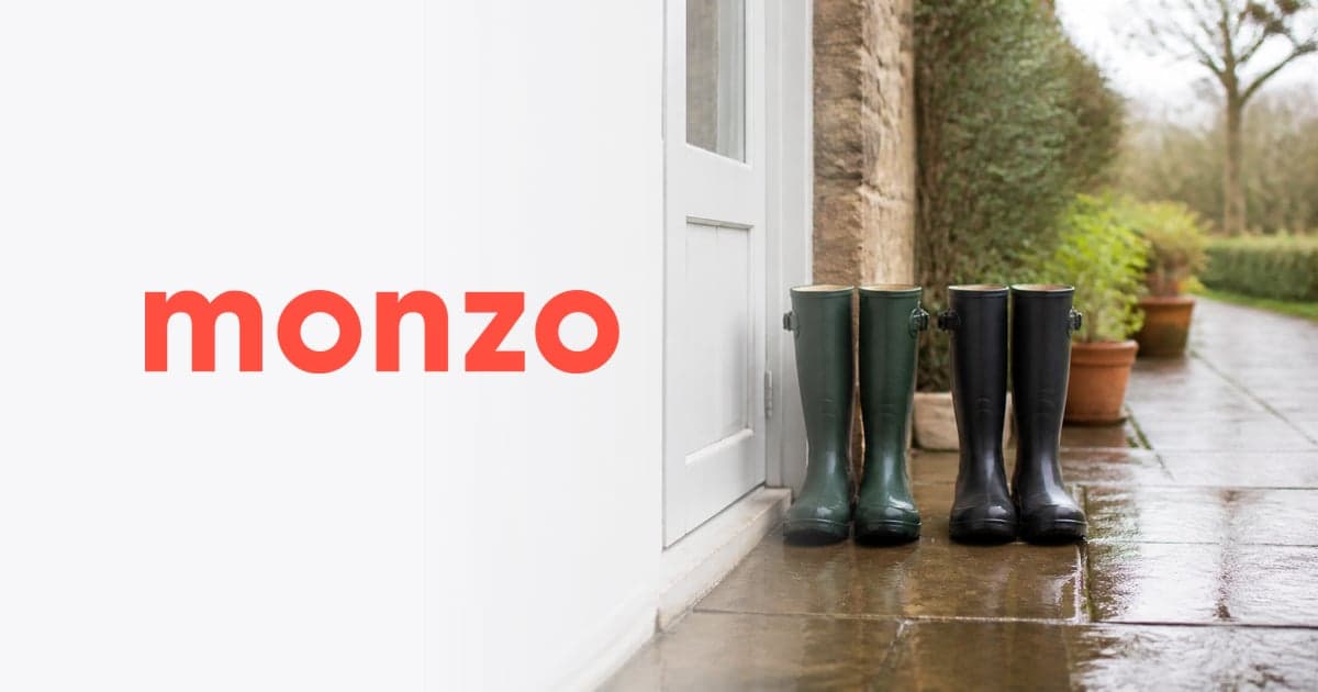 two pairs of wellington boots at a back door beside a wet garden path