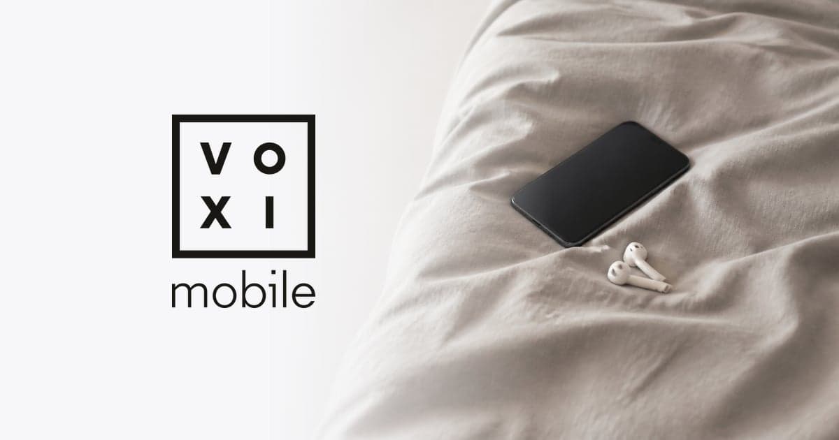 a phone and a pair of earbuds resting on a rumpled duvet