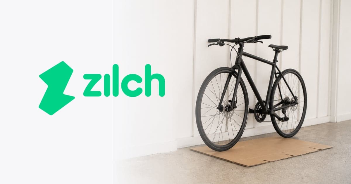 a new bicycle propped against the wall of a bright hallway beside a flattened cardboard box