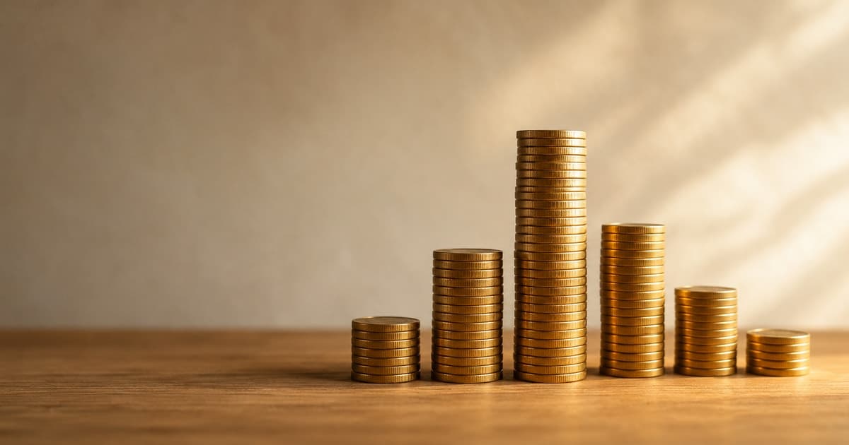 stacks of gold coins of different heights lined up on a wooden table