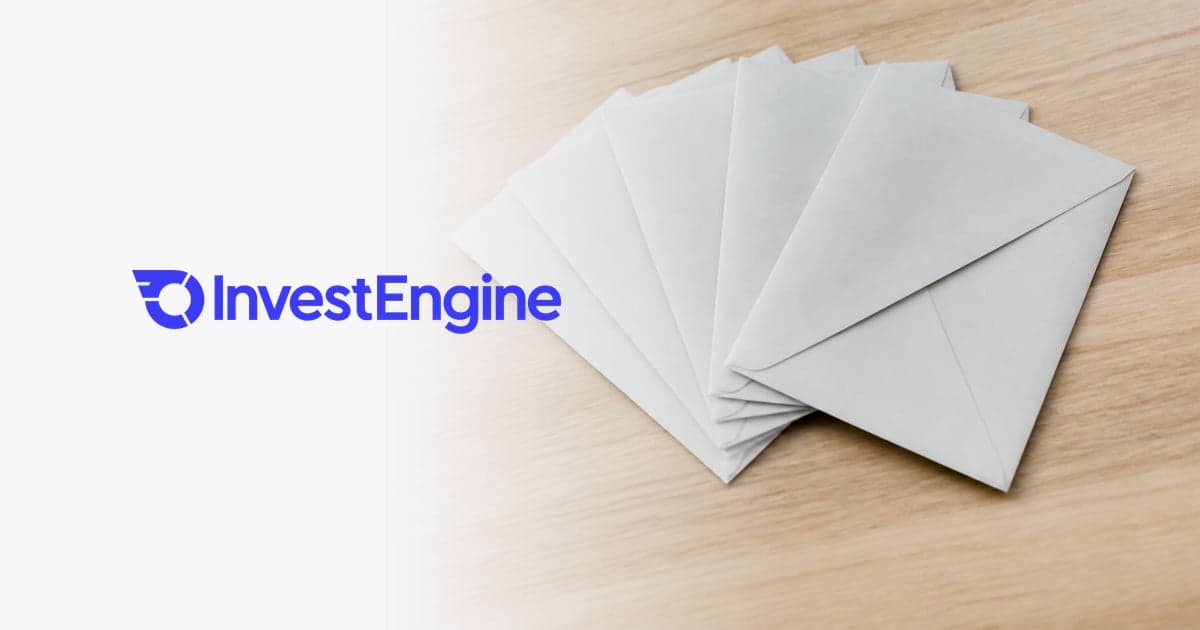 five identical unmarked sealed envelopes fanned across a pale wooden desk