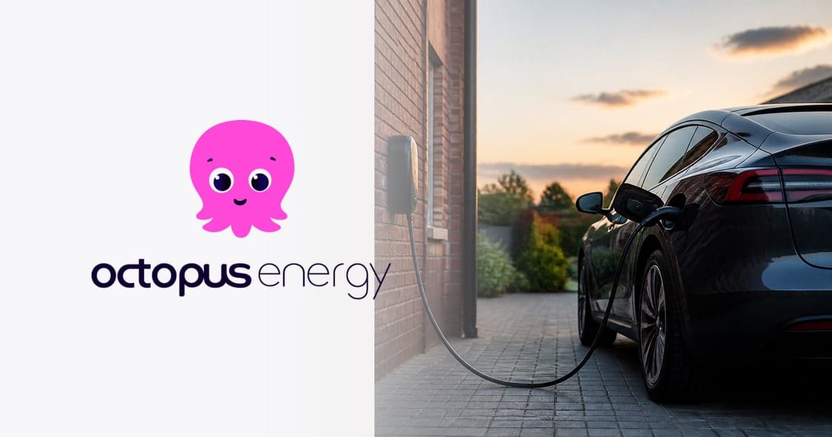 an electric car plugged into a wall-mounted home charger on a block-paved driveway beside a red brick house at dusk