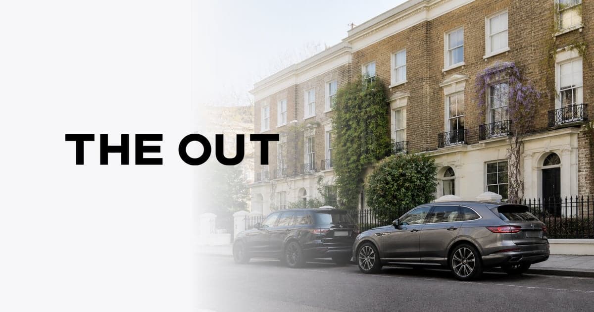 two premium SUVs parked nose to tail on a residential London street outside a row of brick terraced houses, bright morning light