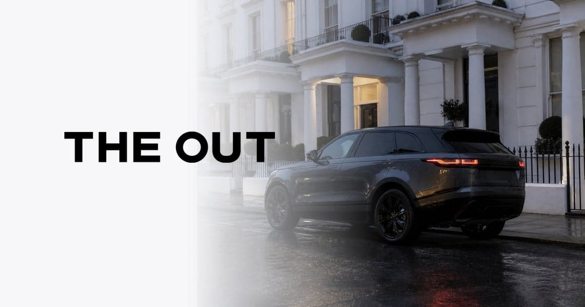 a Range Rover Velar parked on a wet London street outside a terrace of white stucco townhouses at dusk